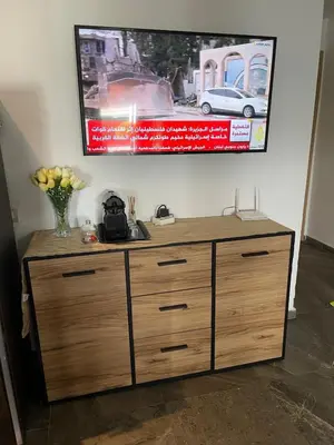 a wooden dresser in a room with a poster on the wall at Bel Appartement à AMWAJ Sidi rahal in Casablanca