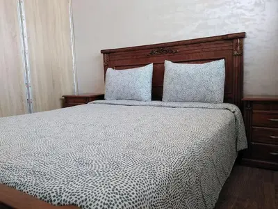 a bedroom with a bed with a wooden headboard and pillows at Appartement bien situé Dahomey city . Bahia beach in Bouznika