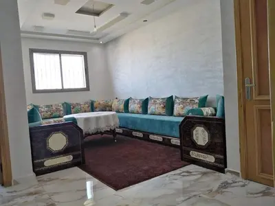 a living room with a blue couch and a window at Appartement bien situé Dahomey city . Bahia beach in Bouznika