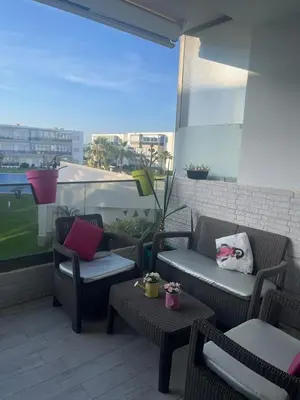 a patio with chairs and tables on a balcony at Superbe appartement en résidence avec piscine in Sidi Rahal