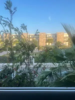 a view of a city from a window with palm trees at Superbe appartement en résidence avec piscine in Sidi Rahal
