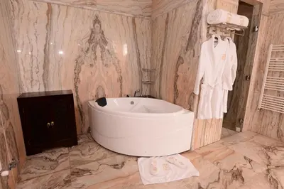 a bathroom with a large tub and a marble wall at THE WHITE PALACE Rabat in Rabat