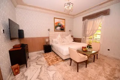 a bedroom with a bed and a table and a television at THE WHITE PALACE Rabat in Rabat