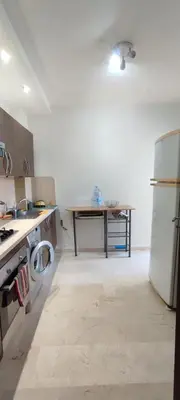 a kitchen with a refrigerator and a table in it at Appartement Résidence fermée in Casablanca