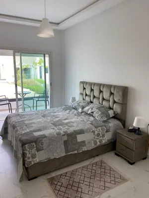 a bedroom with a large bed and a table and chairs at Lovely 4-bedroom condo with pool in Rabat