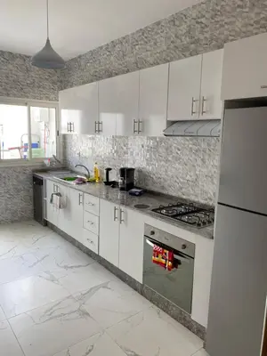 a kitchen with white cabinets and stainless steel appliances at Lovely 4-bedroom condo with pool in Rabat