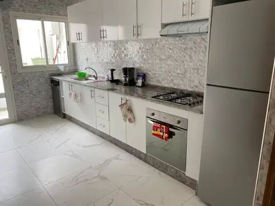 a kitchen with white cabinets and a stove top oven at Lovely 4-bedroom condo with pool in Rabat