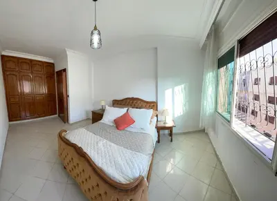 a bedroom with a large bed in a room with windows at Bel Appartement au cœur de BOUZNIKA in Bouznika