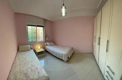 two beds in a room with pink walls at Bel Appartement au cœur de BOUZNIKA in Bouznika