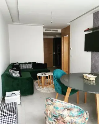 a living room with a green couch and a table at Appartement haut standing au quartier les princesses avec grande terrasse et parking gratuit in Casablanca
