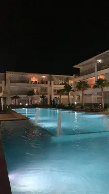 a swimming pool with blue water in front of a building at Appartement à louer dans une résidence balnéaire 3 piscines - RAMOFLORES Sidi Rahal in Sidi Rahal