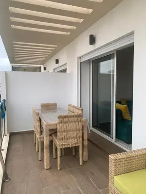a dining room with a table and wicker chairs at Appartement à louer dans une résidence balnéaire 3 piscines - RAMOFLORES Sidi Rahal in Sidi Rahal