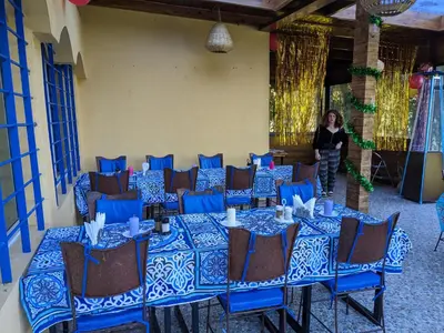 a woman standing in a room with blue tables and chairs at Mesdunes in Azemmour