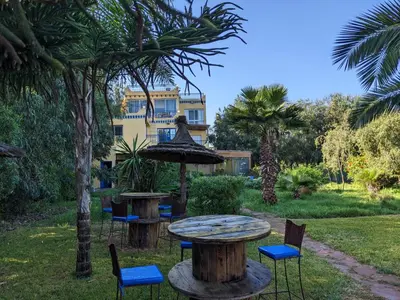 a table and chairs in a garden with a building in the background at Mesdunes in Azemmour