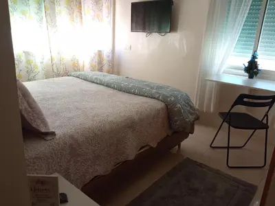 a bedroom with a bed and a chair and a window at Aryam Room in Rabat