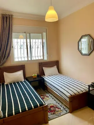 a bedroom with two beds and a window at Échappez à la ville , Appartement près de la nature, entre forêt et plage juste pour les familles in Skhirat