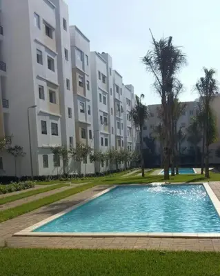a swimming pool in front of a large building at Magnifique Appartement avec Piscine à Tamaris in Tamaris