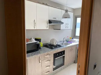 a kitchen with white cabinets and a stove top oven at Appartement blanca beach Sidi Rahal accès direct à la plage in Casablanca