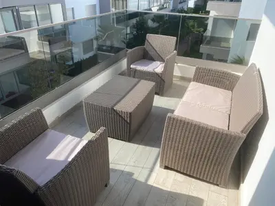 a balcony with wicker chairs and tables on a building at Appartement blanca beach Sidi Rahal accès direct à la plage in Casablanca