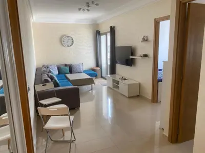a living room with a couch and a tv at Appartement blanca beach Sidi Rahal accès direct à la plage in Casablanca