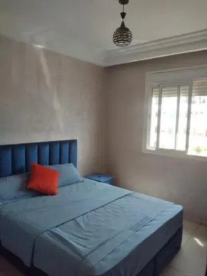 a bedroom with a blue bed with a red pillow at La Perle in Casablanca