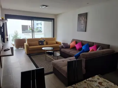 a living room with two couches and a table at Joli appartement à Harhoura in Oulad Kerroum