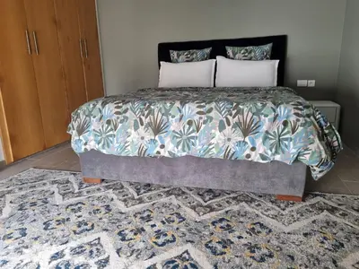 a bedroom with a large bed with a rug at Joli appartement à Harhoura in Oulad Kerroum