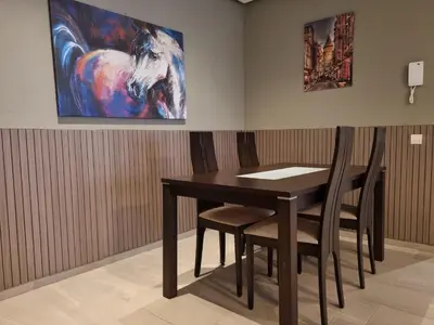 a table and chairs in a room with a painting at Joli appartement à Harhoura in Oulad Kerroum
