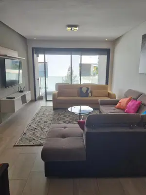 a living room with two couches and a table at Joli appartement à Harhoura in Oulad Kerroum