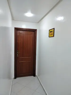 a hallway with a wooden door and white walls at Appartement 11 Casa Voyageurs in Casablanca