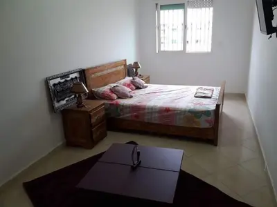 a bedroom with a bed and a table in it at Appt à plage sidi Rahal in Sidi Rahal