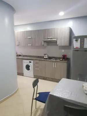 a kitchen with wooden cabinets and a table and a stove at Beach-Side 2-BR Oasis with Private Pool & Parking in Casablanca