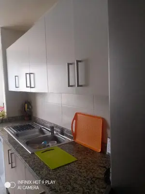 a kitchen with an orange chair next to a sink at Belfakih in Beni Brour