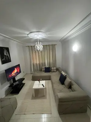 a living room with a couch and a tv at Magnifique appartement proche Arribat Center in Rabat