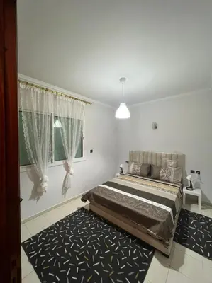 a bedroom with a bed and a window and a rug at Magnifique appartement proche Arribat Center in Rabat