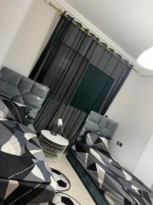 a room with a bed and a table and a window at Magnifique appartement proche Arribat Center in Rabat