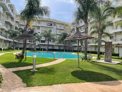 a resort with a swimming pool and palm trees at The garden corner in Bouznika