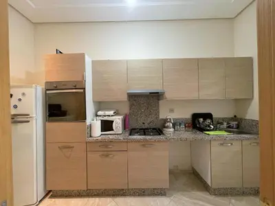 a kitchen with wooden cabinets and a white refrigerator at The garden corner in Bouznika