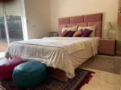 a bedroom with a large bed with a large headboard at The garden corner in Bouznika