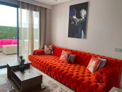 a large orange couch in a living room at Les Jardins de l'Oasis - 2 rooms in Casablanca