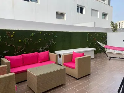 a patio with pink couches and a table and chairs at Les Jardins de l'Oasis - 2 rooms in Casablanca