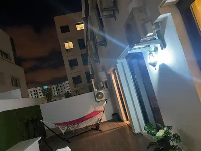 a chair sitting on a balcony at night at Les Jardins de l'Oasis - 2 rooms in Casablanca