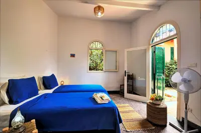 a bedroom with a blue bed and a fan at Charmante Maison 2ch et Bungalow 2ch au Coeur de l'Oasis in Casablanca