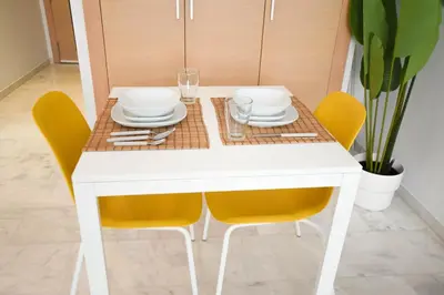 a table with yellow chairs and a white table with plates and glasses at YourPlace - Prestigia - Hay Riad in Rabat
