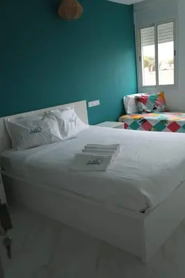 a white bed in a bedroom with a blue wall at appartement de luxe front mer à DAR BOUAAZA in Dar Bouazza