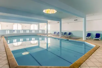 a large swimming pool with blue chairs in a building at appartement de luxe front mer à DAR BOUAAZA in Dar Bouazza