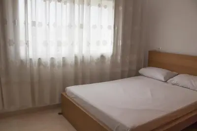 a bedroom with a bed and a window with curtains at Cozy Apartment in Rabat