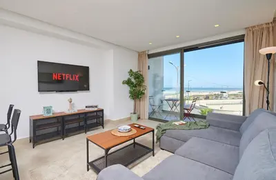 a living room with a couch and a tv at TheCasaEdition - Bel Azur - Sea View & Hassan II Mosqué Residency in Casablanca