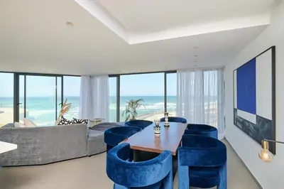 a living room with a table and blue chairs at TheCasaEdition - Bel Azur - Sea View & Hassan II Mosqué Residency in Casablanca
