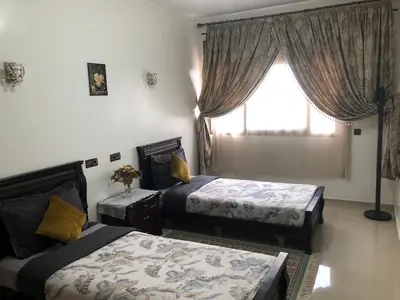 a bedroom with two beds and a window at Bel Appartement spacieux 3 pièces avec double salon Paisible & Proche de la Gare d'Agdal in Rabat